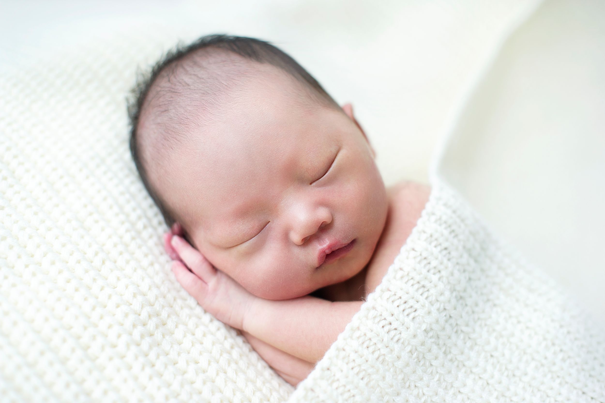 Newborn wrapped in a cream knit blanket, taken by Phoebe Lee Photo in Toronto
