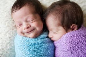 Smiling twin newborns wrapped in blue and purple blankets, captured by Phoebe Lee Photo in Toronto