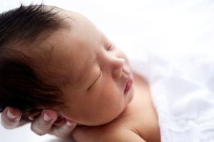 Newborn baby sleeping peacefully in a white swaddle, captured by Phoebe Lee Photo in Toronto