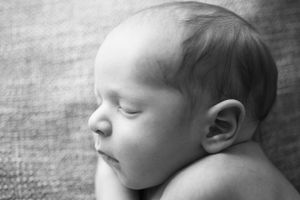Side profile of a sleeping newborn on a textured blanket, captured in black and white by Phoebe Lee Photo in Toronto