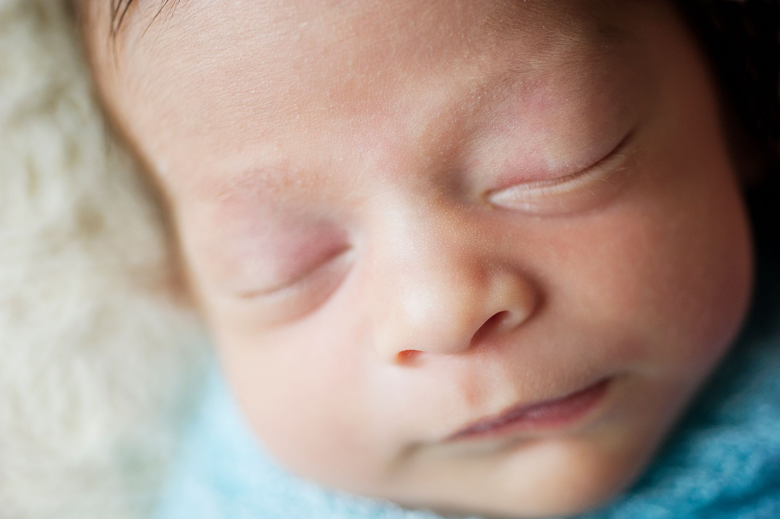 Peaceful newborn boy in a blue swaddle during a Toronto newborn session by Phoebe Lee Photo