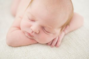 Newborn baby resting head on arms, peacefully asleep on a soft surface, by Phoebe Lee Photo in Toronto