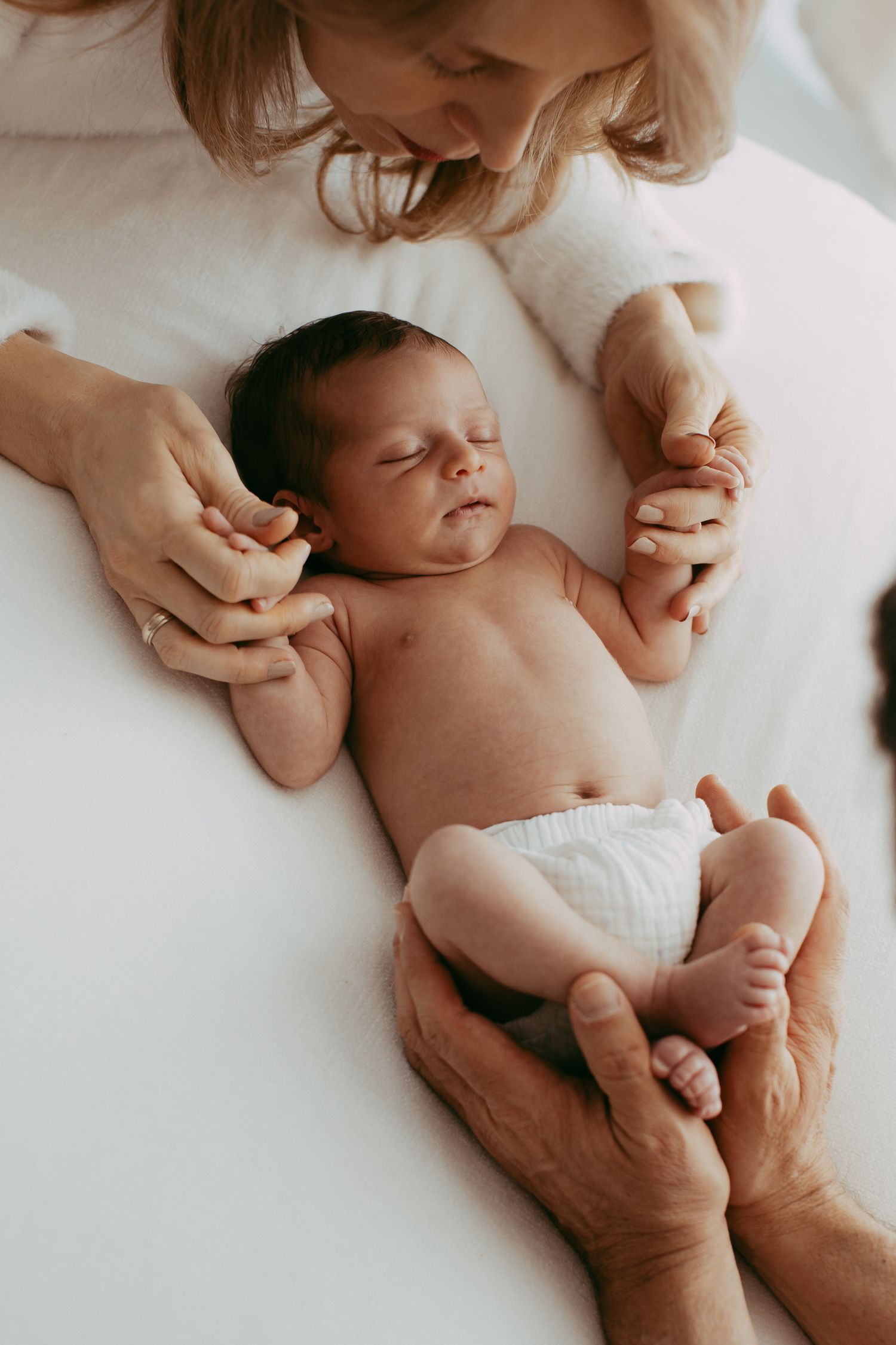Gentle hands cradle newborn baby during intimate photo session.