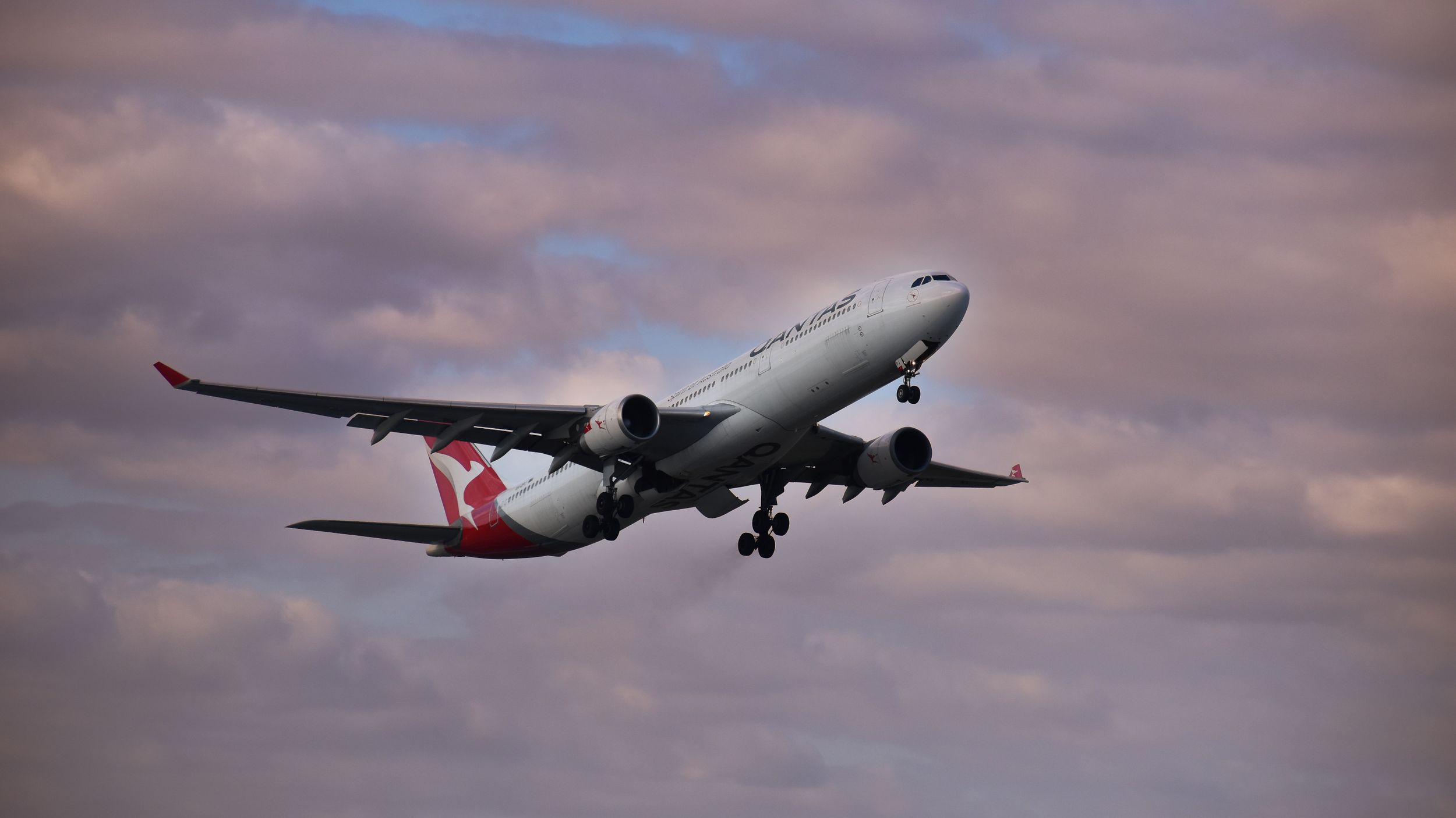 A Turkish Airlines Airbus A330 aircraft ascending into a dramatic cloudy sky during sunset.