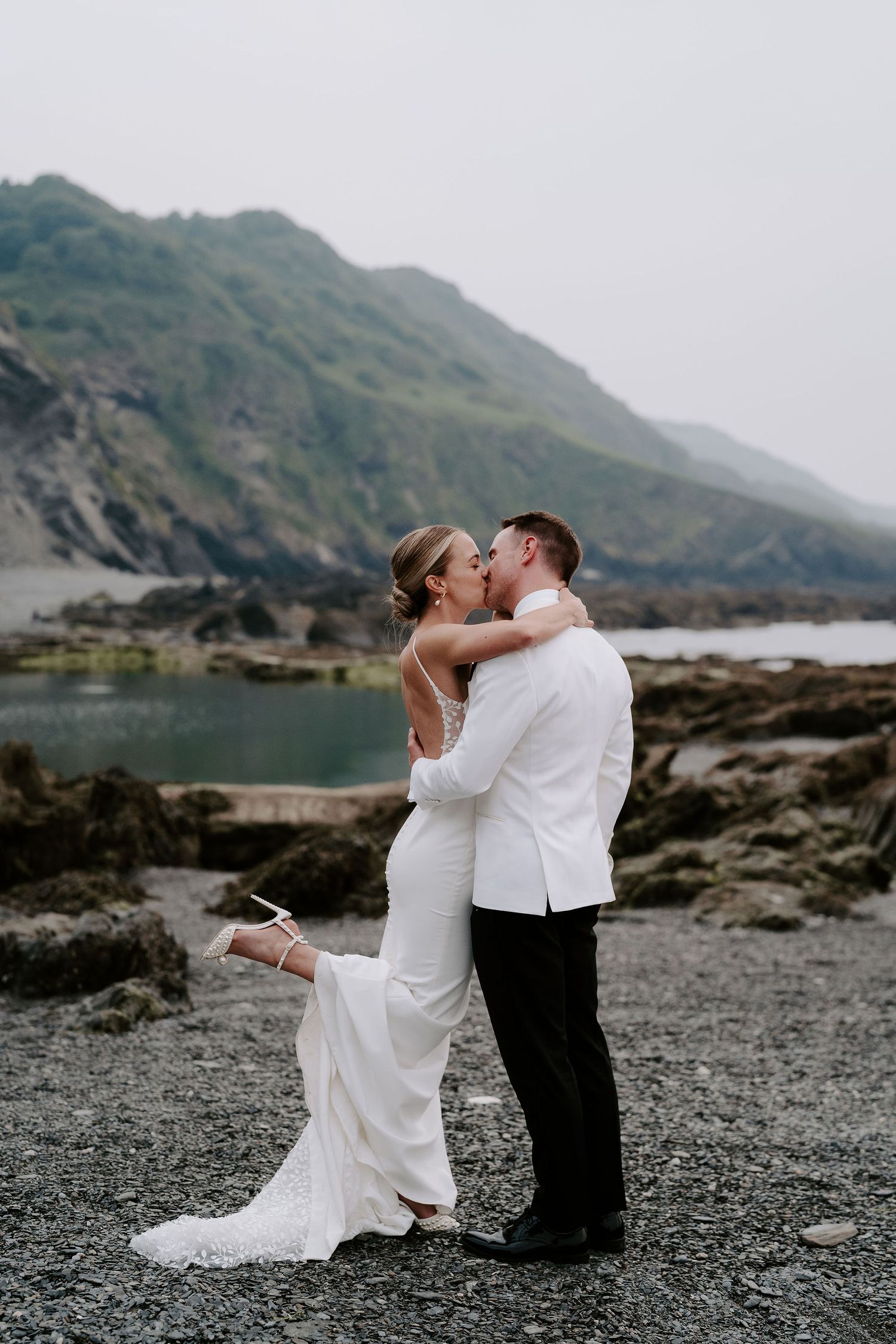 Bride and Groom kissing on beach during sunset at tunnels beach wedding venue in north Devon