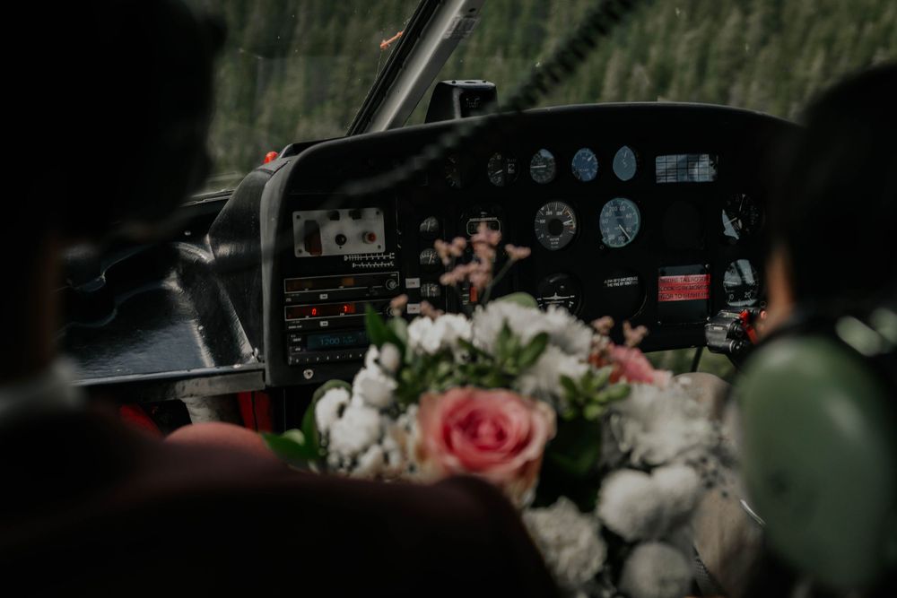 Pink roses and white flowers rest on the dashboard of an aircraft cockpit with flight instruments visible in background.