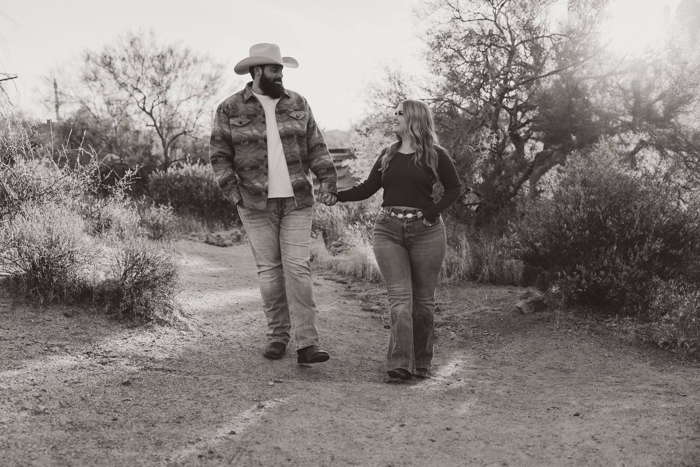 A vintage black and white photo shows a couple gazing into each others eyes while holding hands.