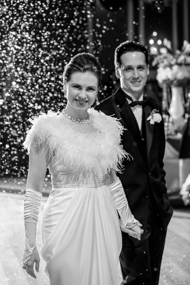 A formal wedding portrait with sparkling lights and falling snow in the background.