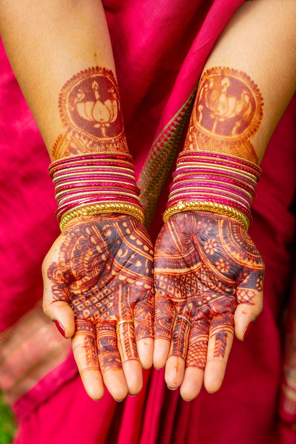 Detailed henna mehndi designs adorning palms with traditional bridal bangles and red clothing in Indian wedding ceremony.