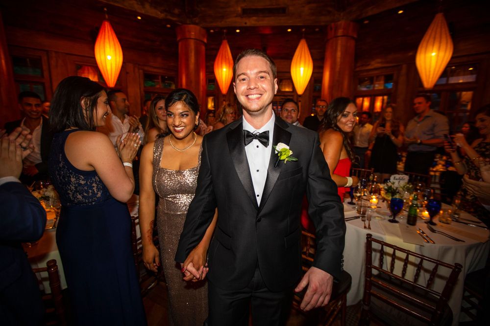 Reception guests smile during an elegant evening wedding celebration with glowing orange lanterns and formal decor.