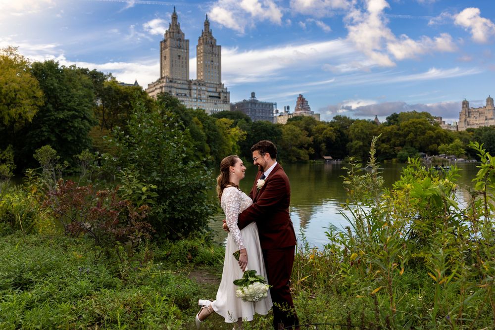 A couple embraces at Central Park Lake with the iconic El Dorado towers rising behind them on a sunny afternoon.
