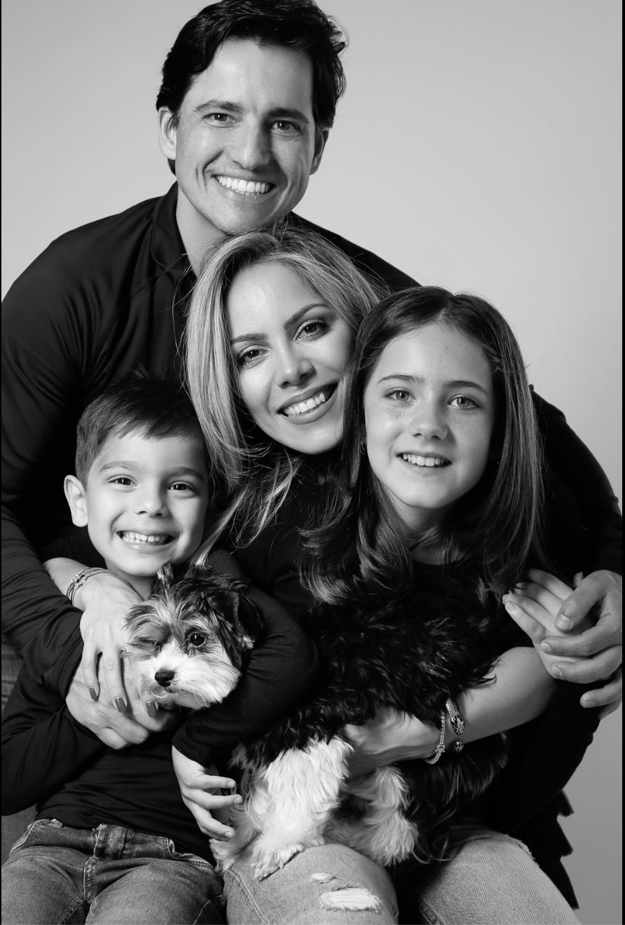 Black and white family portrait with parents, two children, and a small dog posing together.