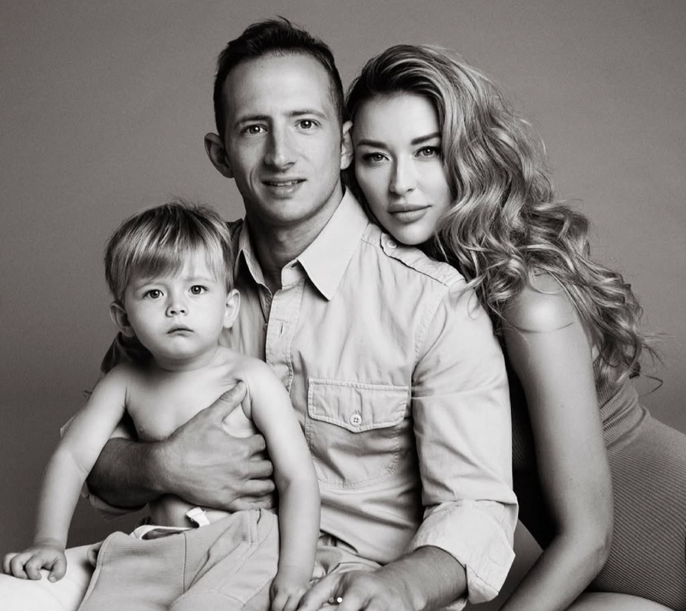 Black and white family portrait of couple with toddler child in studio.