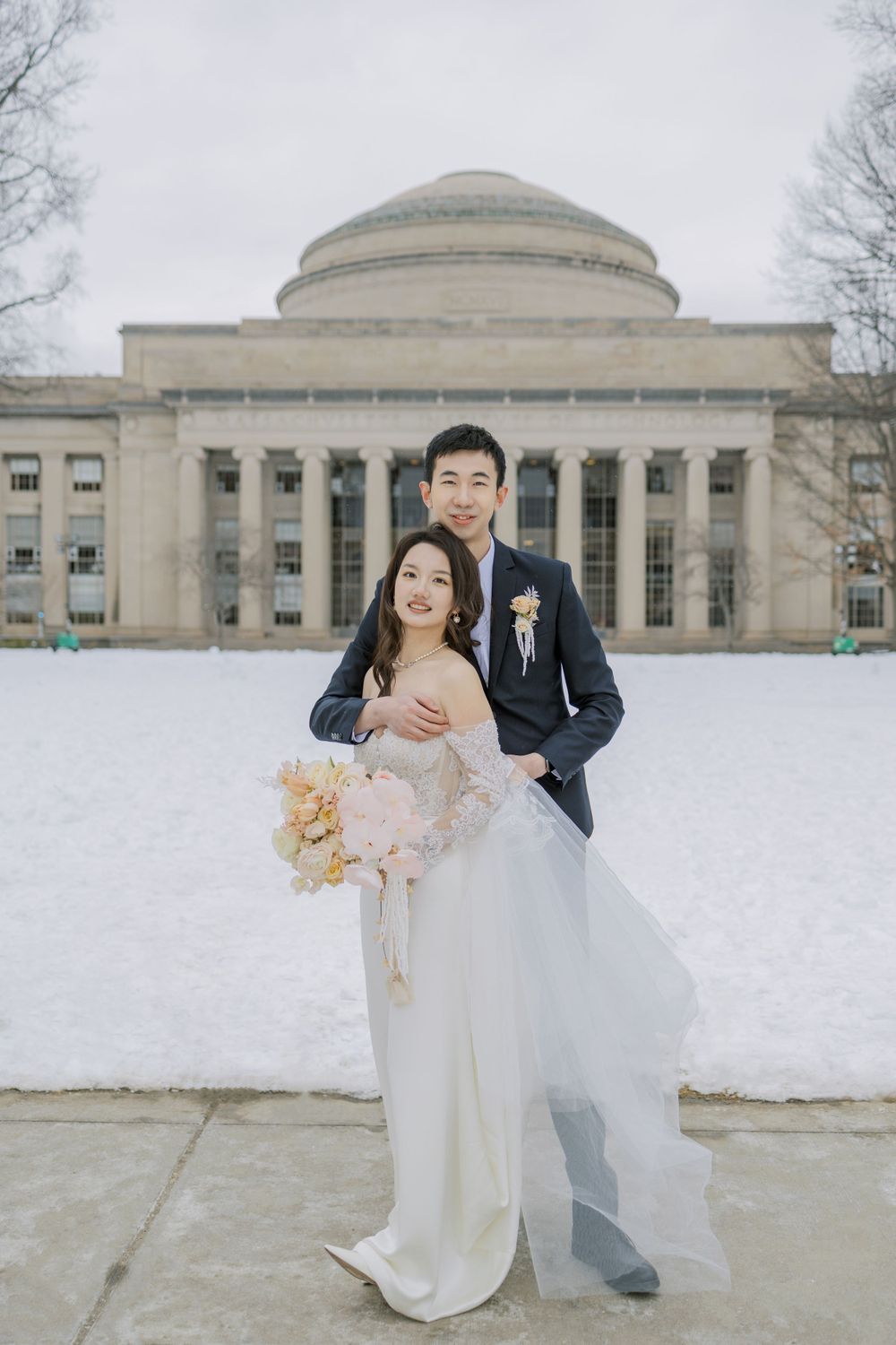 A winter wedding photo featuring a couple in front of MIT's iconic dome building.