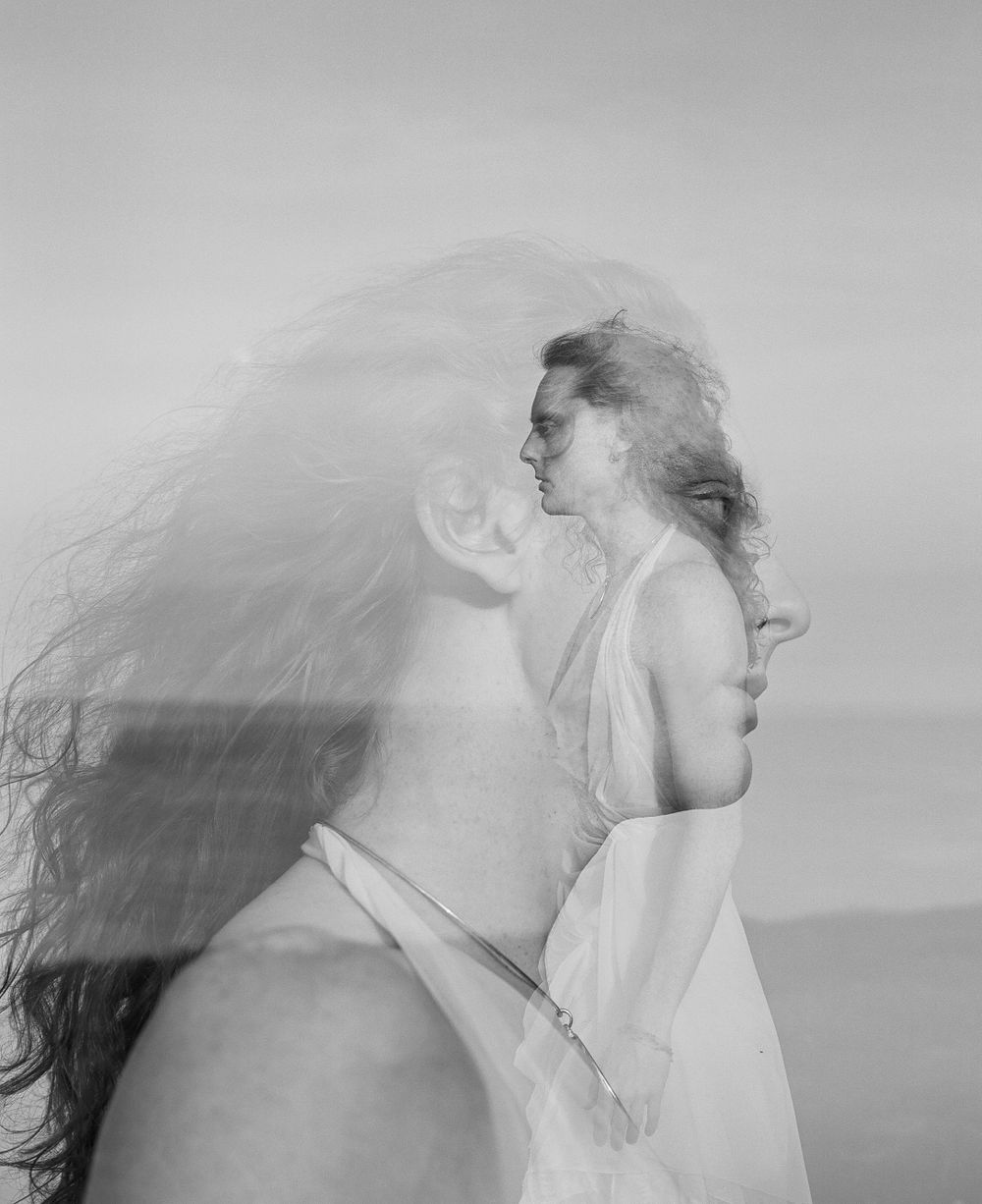 Double exposure portrait creating ethereal effect against seaside backdrop.