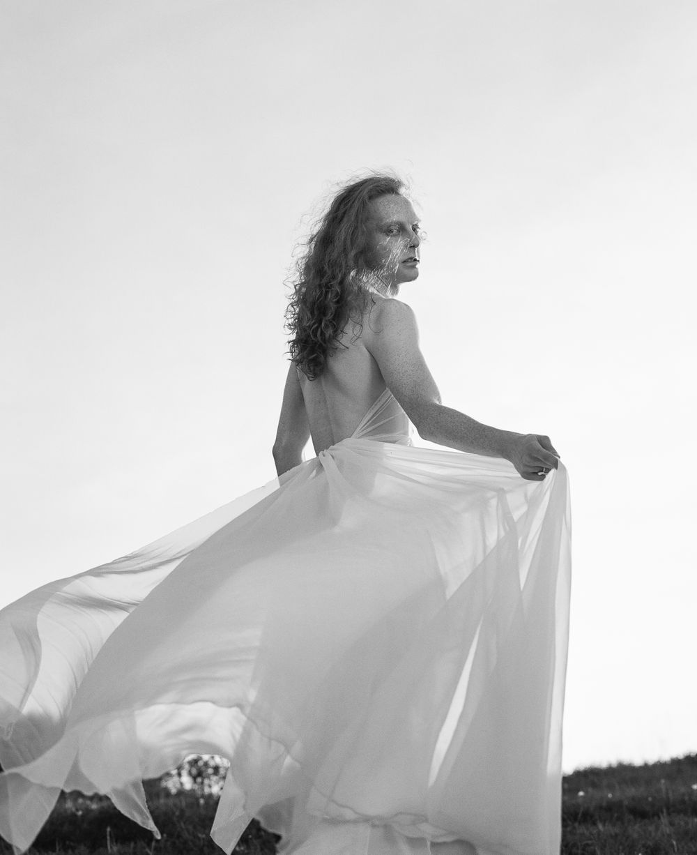 Black and white photo of flowing white dress caught in motion outdoors.