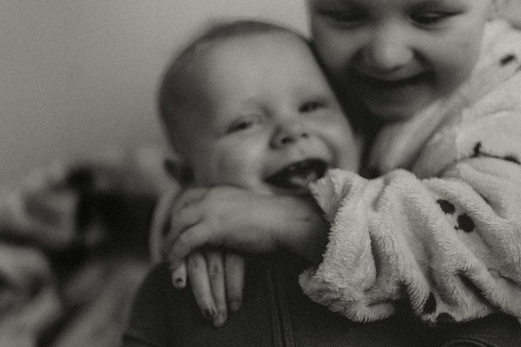 Black and white photo of two laughing babies hugging together.