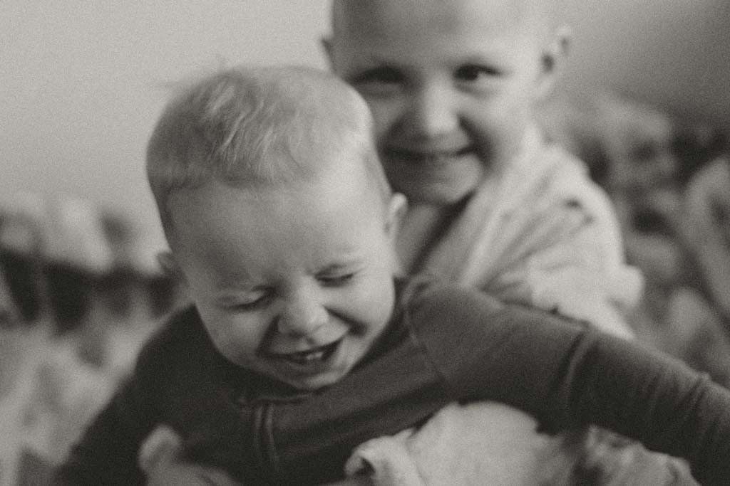 Black and white photo of two giggling babies embracing joyfully.