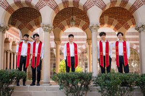 Group in matching red and white outfits standing in an elegant archway corridor with ornate architecture.
