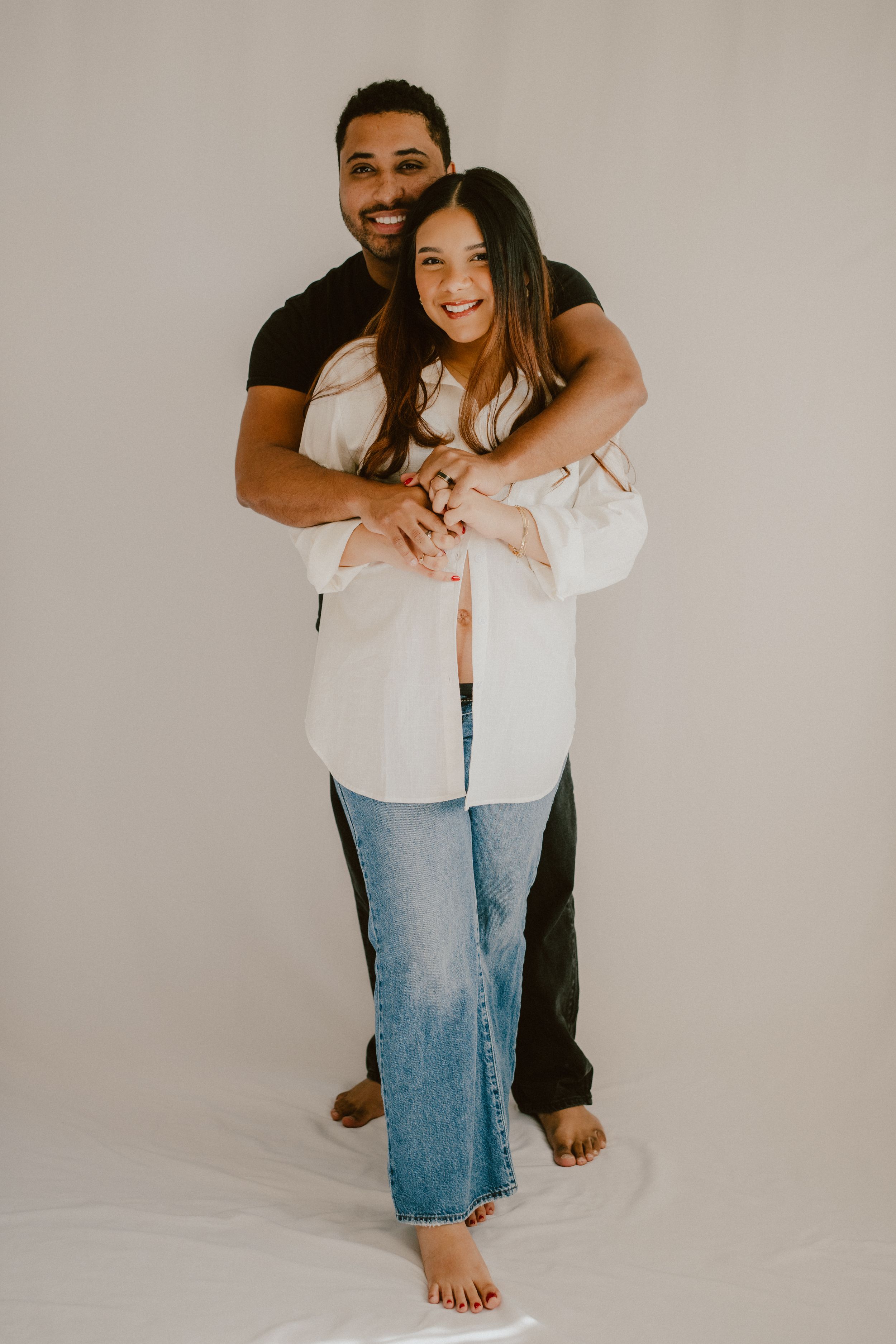 Casual studio portrait with white shirt and jeans against neutral background.