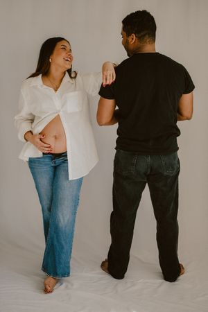 Casual studio portrait showing playful interaction in white shirt and denim.