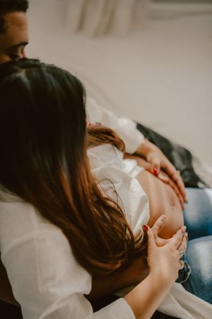 An intimate maternity photo showing a couple's hands resting on a pregnant belly.