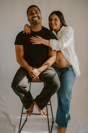 A candid maternity photo of an expecting couple embracing and smiling.