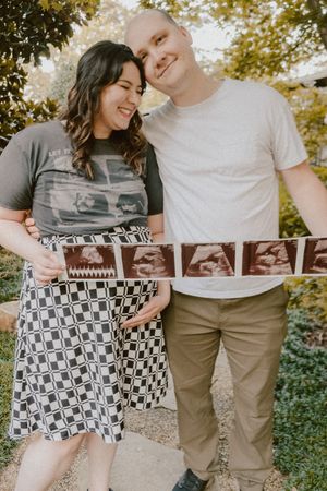 Outdoor maternity photo featuring ultrasound strip and black and white checkered dress.