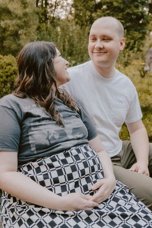 A joyful outdoor maternity photo session with natural sunlit background.