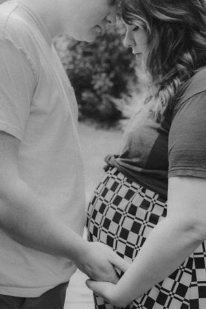 Intimate black and white maternity photo showing tender moment between couple.