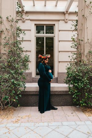 Maternity photo showing silhouette against architectural backdrop with flowering vines.