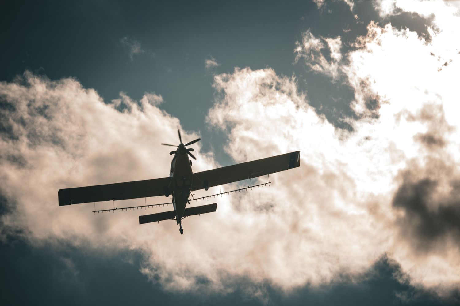 Silhouettes of small aircraft against dramatic cloudy sky.