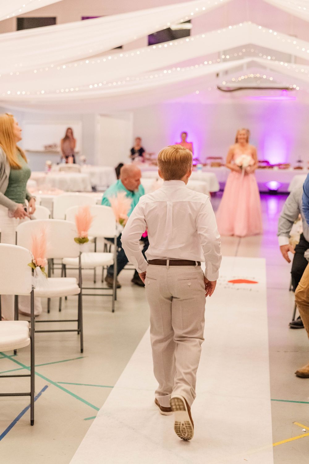 Wedding reception venue with purple uplighting and elegant white draping creating an ethereal atmosphere.