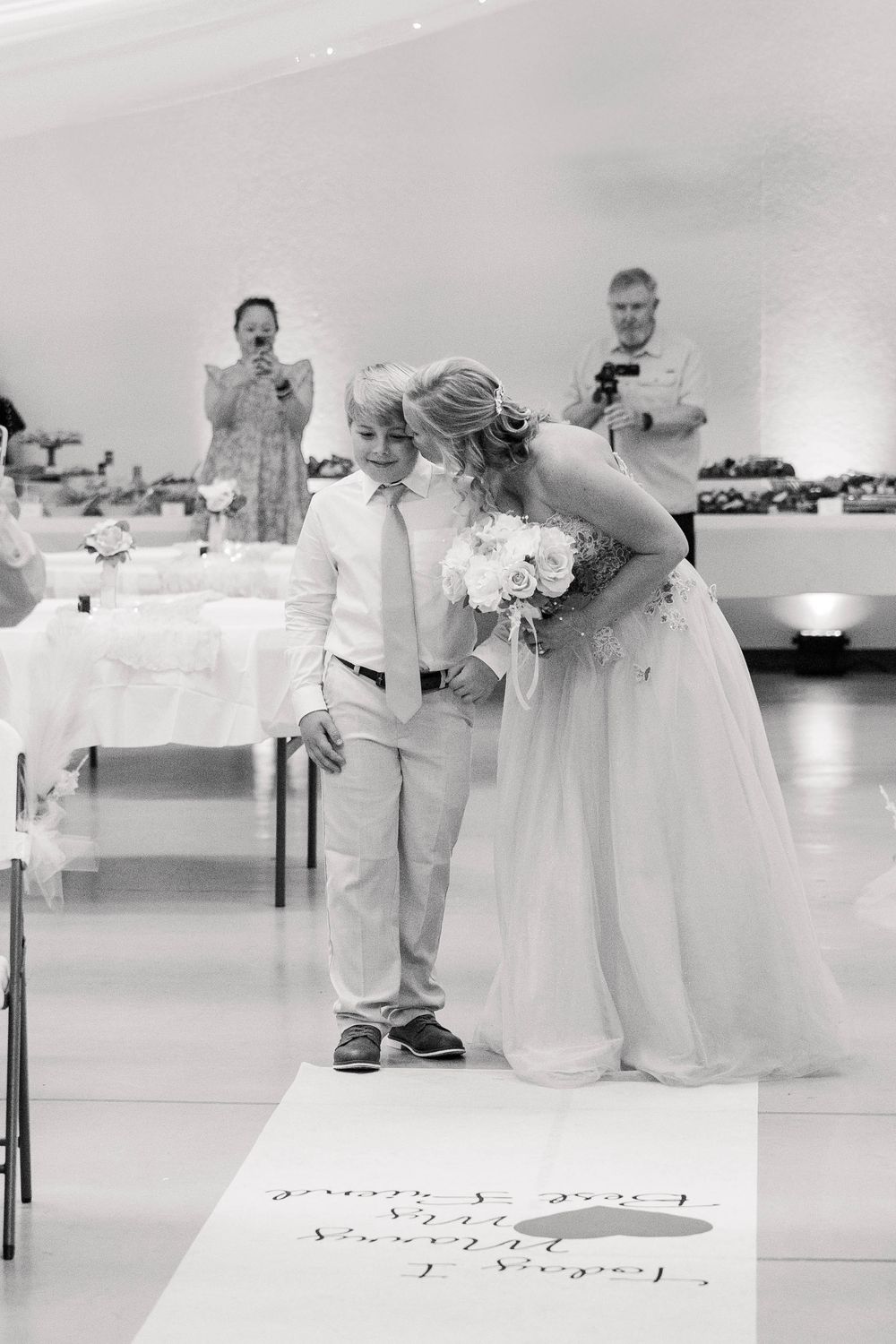 Black and white wedding reception photo showing formal dining setup and dance floor area.