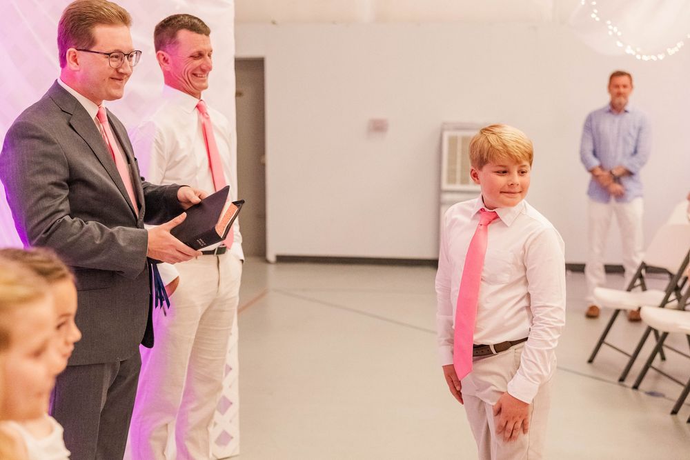 Modern wedding reception space with elegant pink and white decorations and ambient lighting.