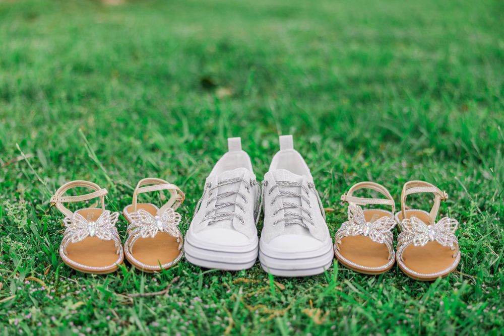 Wedding shoes arranged on grass including white sneakers and gold sandals.