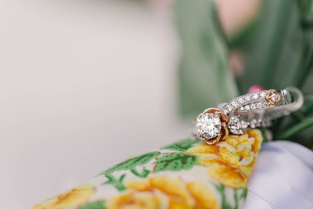 Diamond engagement ring and wedding bands displayed on floral fabric.