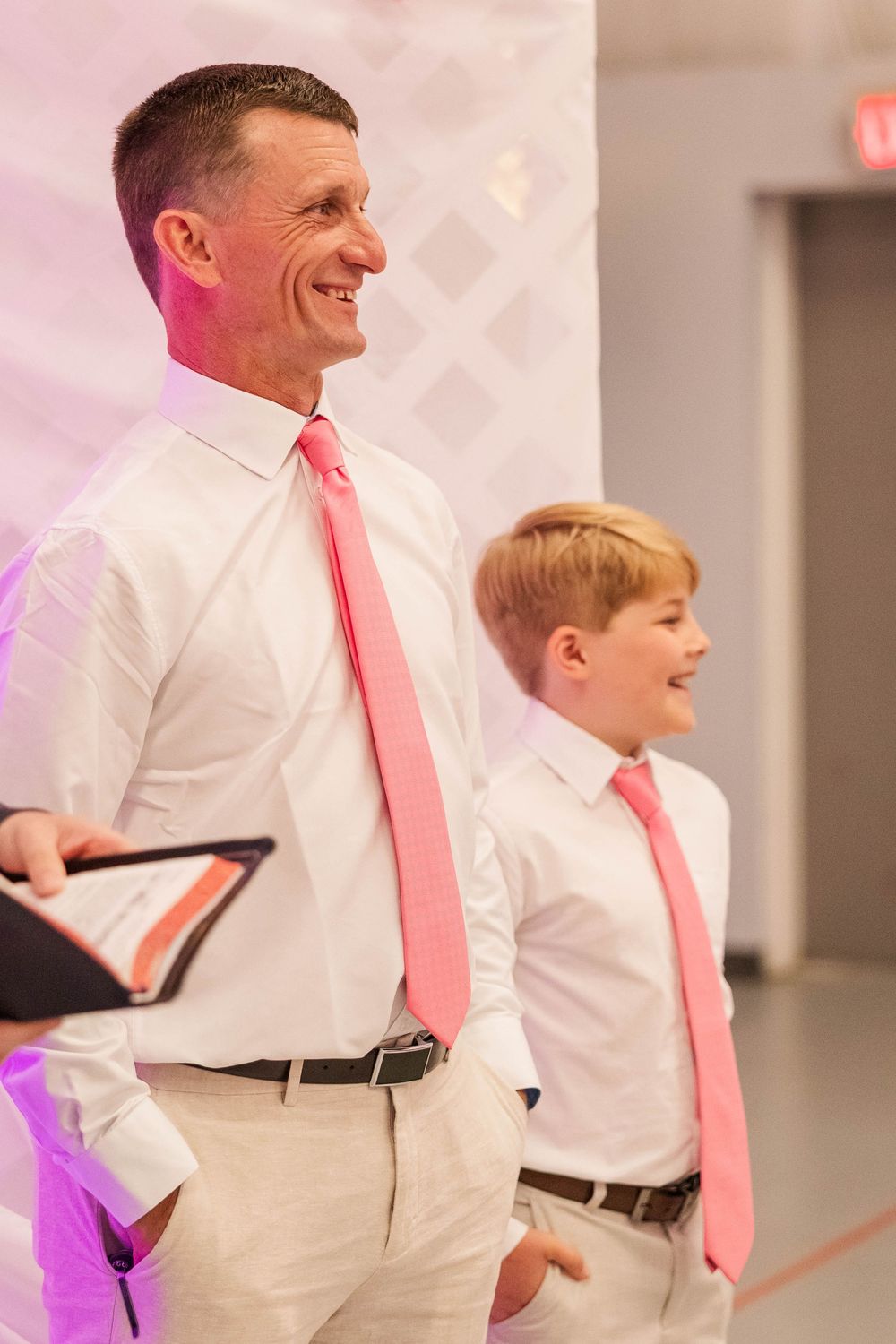 Wedding party members stand together wearing coordinating pink ties and formal attire.
