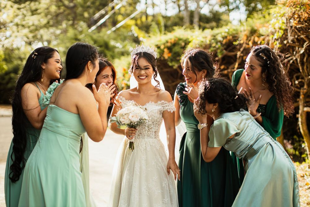 Candid moment of bridesmaids in green dresses sharing laughter during wedding celebrations.