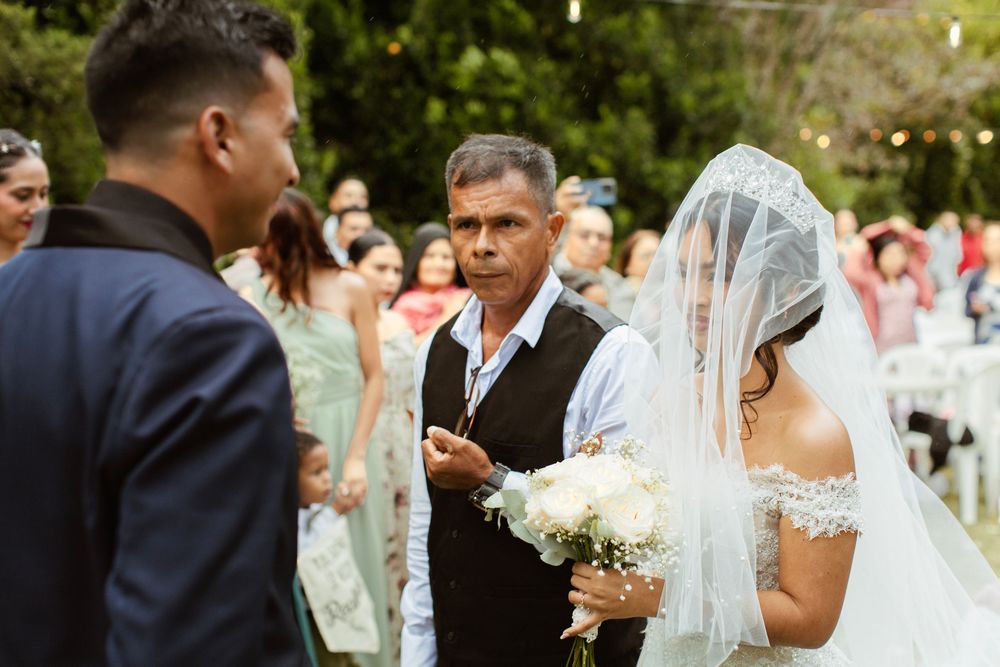 A couple exchanges vows during an outdoor wedding ceremony with guests and officiant in attendance.