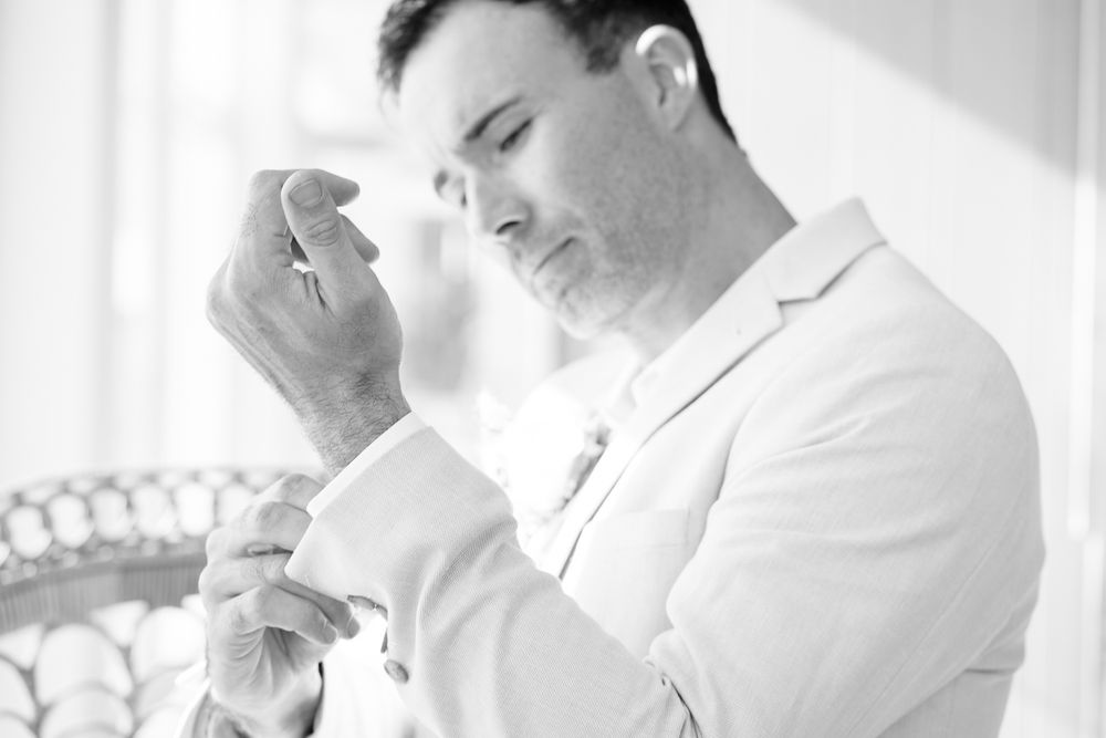 Someone in a white coat carefully holds and examines a small object in their hands.