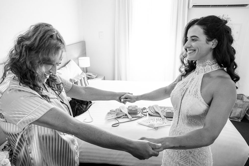 A candid black and white moment shared between two people getting ready in a bright sunlit room.
