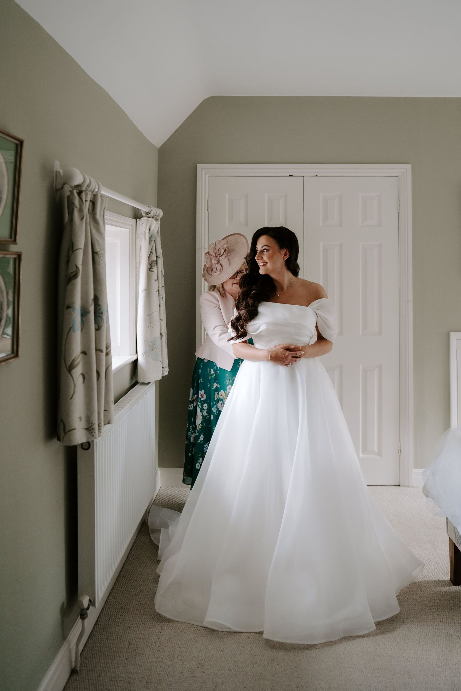 brides mum helping bride get into wedding dress at the new inn cirencester