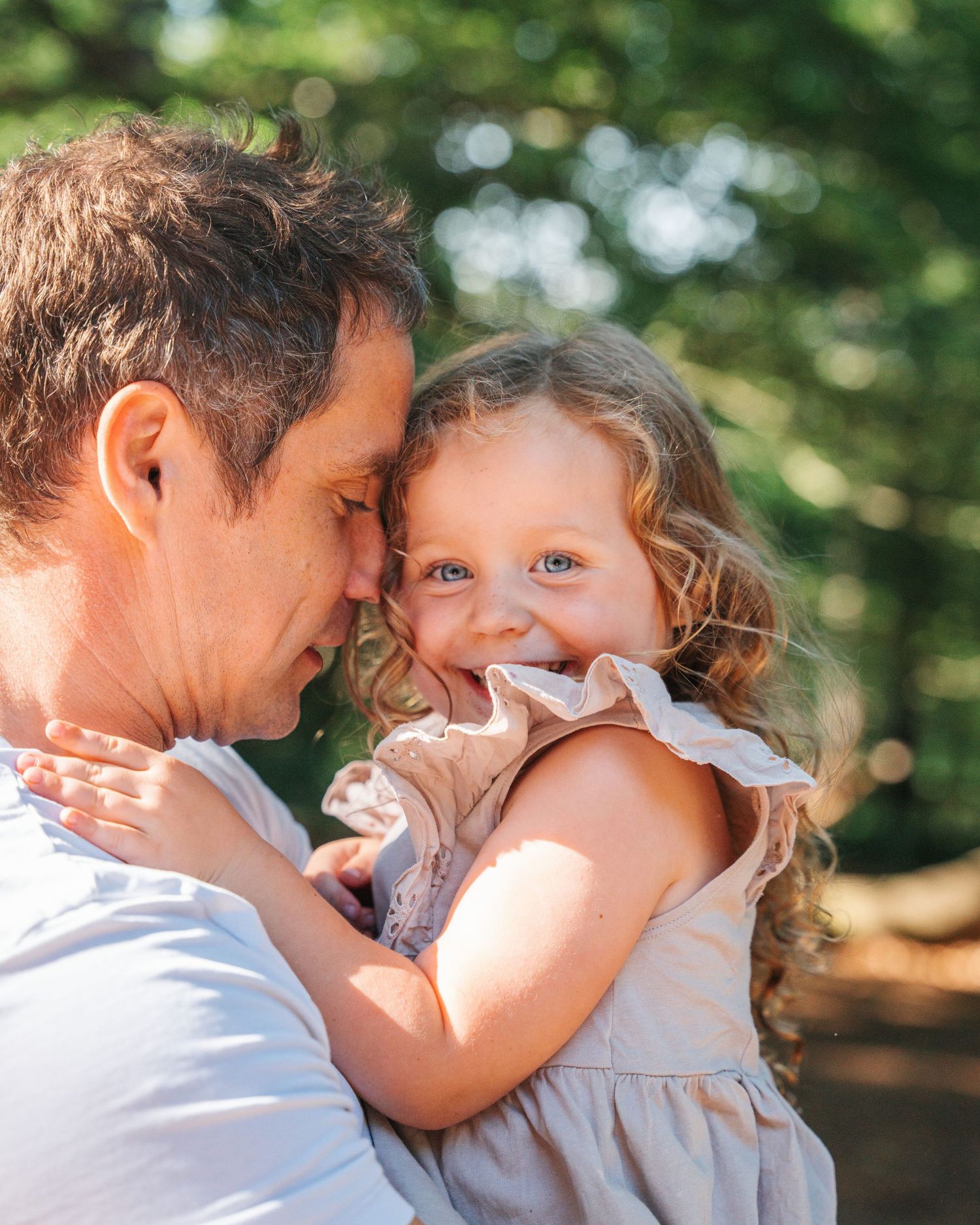 An intimate moment captured between parent and child outdoors with soft natural lighting.