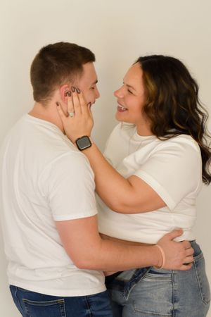 Couple in white shirts sharing intimate moment against neutral background.