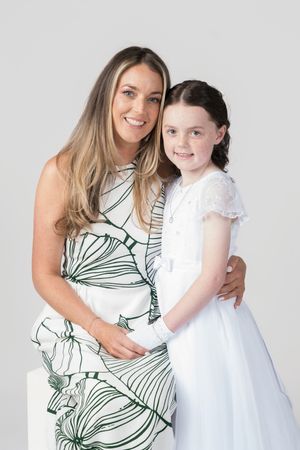 A pair wearing white and patterned dresses pose together in a series of studio portraits.