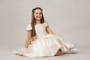A person in a white dress lying on a light gray backdrop in various graceful poses.