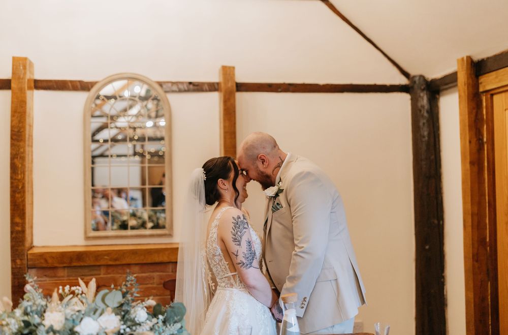 Two people sharing an intimate moment in a rustic chapel with wooden beams and a vintage window in the background.