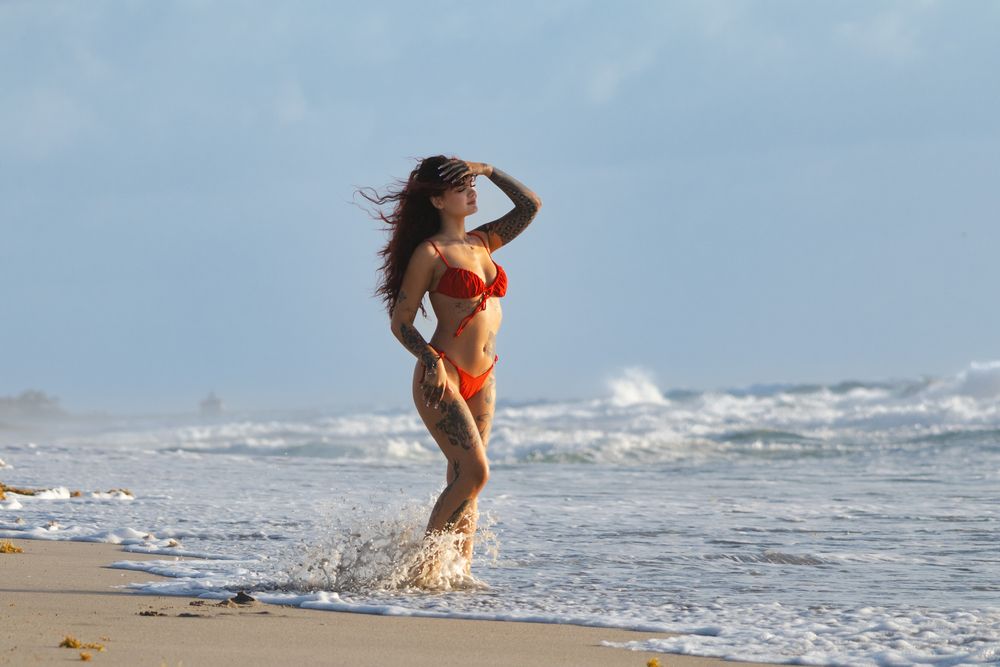 Person splashing in ocean waves on sunny beach day.