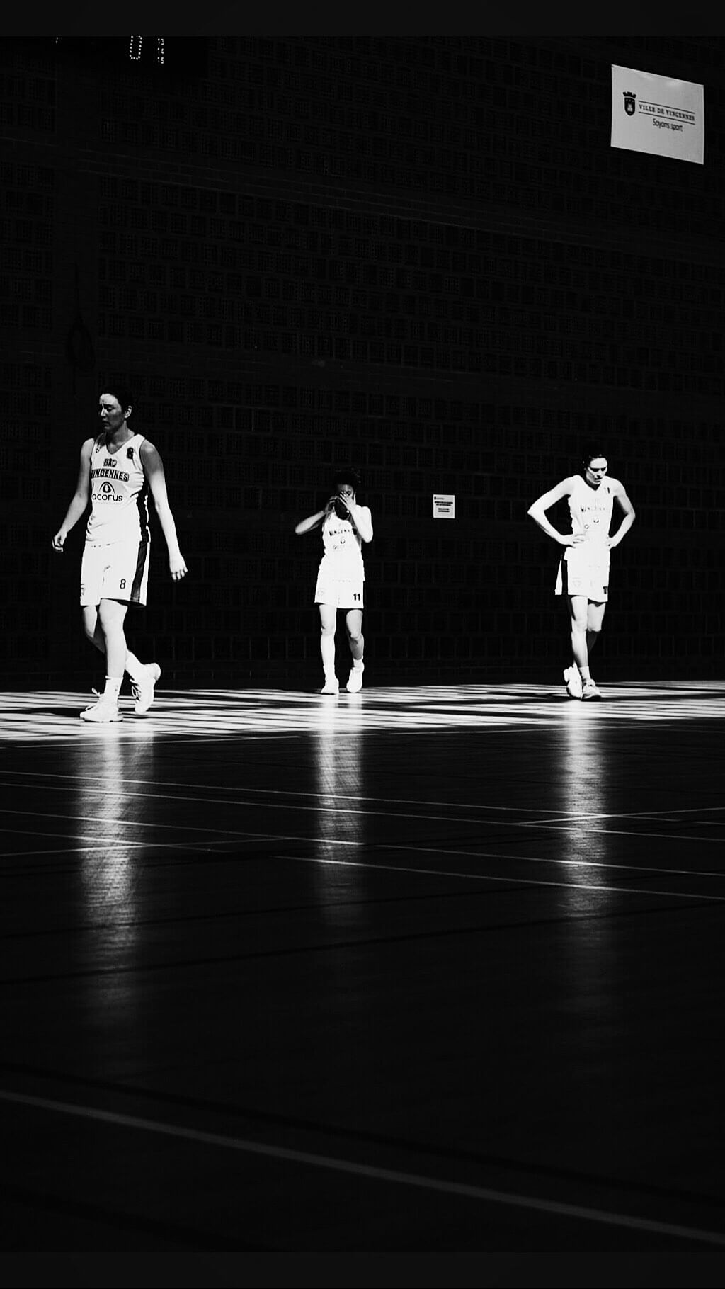 Dancers in white outfits perform on a dark stage creating dramatic silhouettes against the black background.